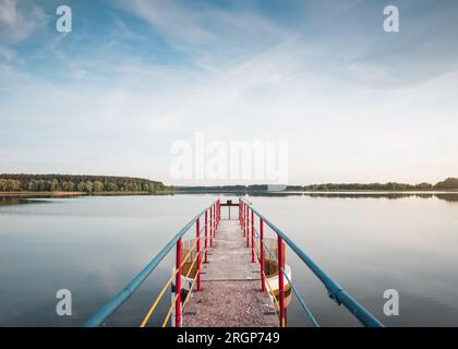 Scena estiva sul lago: Foto simmetrica del ponte e riflesso della foresta sullo sfondo Foto Stock