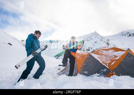 Due sciatori usano gli sci come chitarre aeree, jam session al basecamp Foto Stock