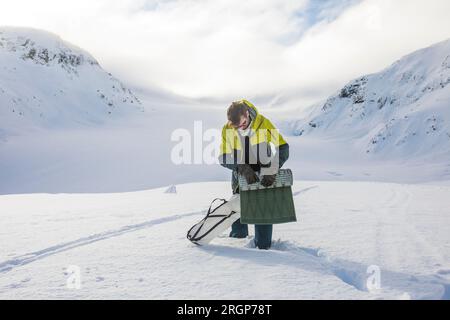 L'alpinista si arrotola su una zona notte, dietro le montagne innevate. Foto Stock