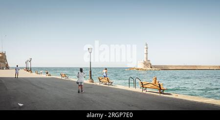 Passeggiata sul mare nel porto di Chania con vista sul faro e sul frangiflutti. Pochi sentieri pedonali lungo il vecchio lungomare del porto in una giornata di sole. Foto Stock