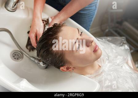Un parrucchiere lava i capelli di una donna Foto Stock