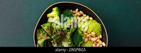 Striscione per colazioni salutari, insalata di bietole con fagioli e cetrioli, avocado e broccoli cosparsi di diversi semi, un piatto di cibo Foto Stock