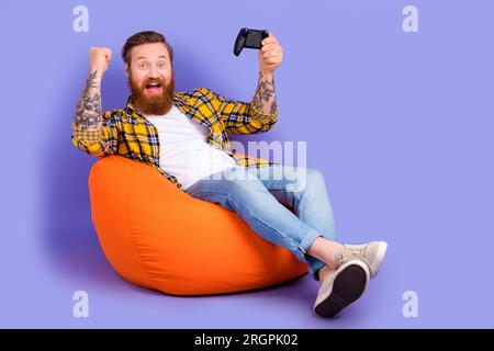 Foto di un uomo felicissimo e allegro che indossa abiti alla moda festeggia il successo vinci la competizione spazio vuoto isolato su sfondo viola Foto Stock