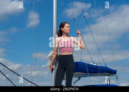 Donna sportiva appoggiata al sole contro l'albero di una barca. Yachting Life. Foto Stock