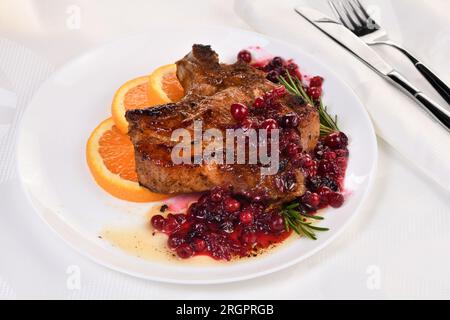 Braciole di maiale fritte servite con salsa ai mirtilli con arancia e rosmarino. Sono eleganti per un pranzo o una cena. Foto Stock