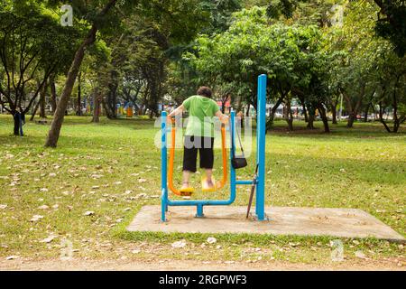 Una donna anziana che si esercita in un parco cittadino a Bangkok in Thailandia. Foto Stock