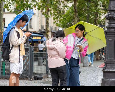 Tre amici giapponesi con ombrelli nella piovosa Parigi, Francia. Foto Stock