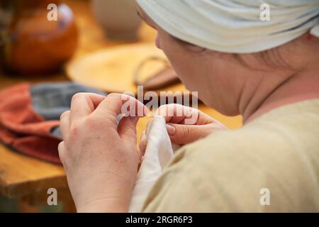 Italia, Lombardia, rievocazione storica medievale, sarta cucisce i vestiti a mano Foto Stock