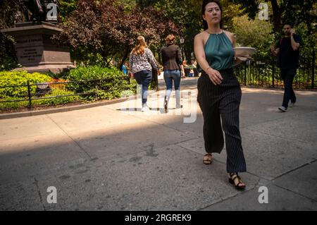 I lavoratori con i loro pranzi da asporto camminano attraverso il Madison Square Park a New York mercoledì 9 agosto 2023. (© Richard B. Levine) Foto Stock