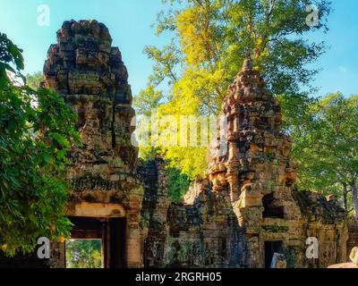 La tela della natura: Pittoresche torri antiche nella foresta autunnale cambogiana di Preah Khan. Foto Stock