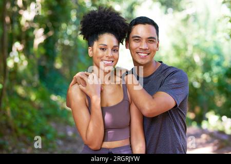 Coppie giovani e felici si mettono in posa nella foresta indossando abbigliamento attivo e facendo escursioni su sentieri per il fitness Foto Stock
