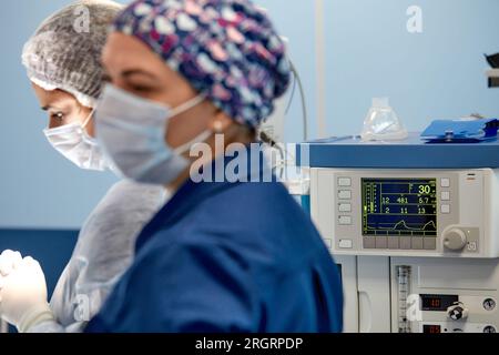 chirurgo che tiene traccia delle funzioni vitali del corpo durante la chirurgia cardiaca. Chirurgo che guarda il monitor medico durante l'intervento chirurgico. Medico controllo monito Foto Stock