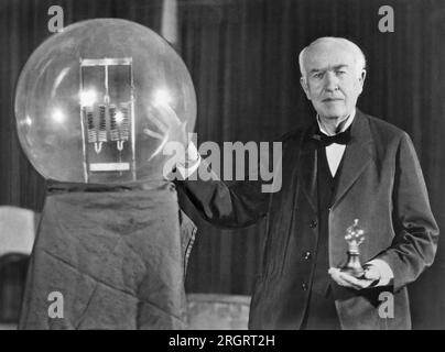 Orange, New Jersey: 16 ottobre 1929 noto inventore Thomas Edison al banchetto d'oro del giubileo della lampadina in suo onore. Espone nella sua mano una replica della sua prima lampada a incandescenza di successo che ha dato 16 candele di illuminazione, in contrasto con la lampada più recente, una lampada da 50.000 watt, 150.000 candele. Foto Stock