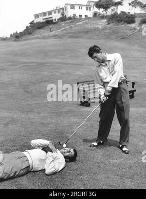 California: 1953 circa Dean Martin sembra essere pronto a scappare da una tee che Jerry Lewis sta spaventosamente tenendo in bocca. Foto Stock