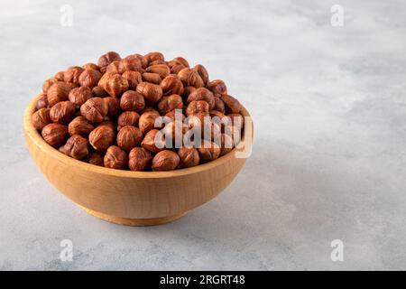 Un recipiente pieno di nocciole sbucciate su sfondo luminoso, primo piano Foto Stock