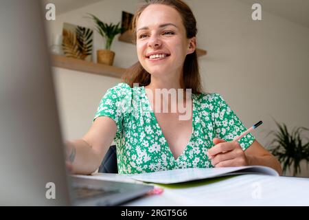 concetto di e-learning, giovane donna adulta che impara online a casa utilizzando un computer portatile. Foto Stock