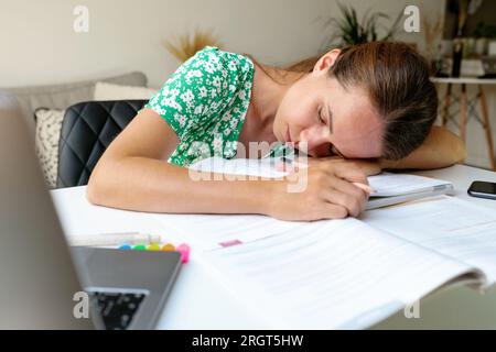 Donna stanca e sovraccarica studentessa universitaria che dorme alla scrivania. Foto Stock