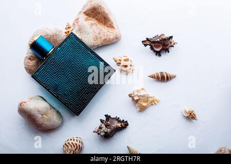 Concetto di profumo con note di mare. Bottiglia di profumo in vetro smerigliato con ciottoli a conchiglia Foto Stock