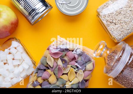 Donazioni di cibo con cibo in scatola su sfondo giallo tavolo Foto Stock