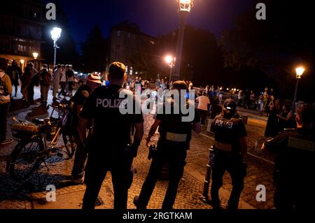 Berlino, Germania. 11 agosto 2023. Gli agenti di polizia sgomberano il ponte di Admiralsbrücke dopo una denuncia da parte dei residenti. Il quartiere berlinese di Friedrichshain-Kreuzberg, particolarmente popolare tra i festaioli, vuole utilizzare un nuovo metodo per garantire che le persone che festeggiano per le strade siano più tranquille e meno fastidiose per i residenti. A tale scopo, è stato installato un misuratore di rumorosità testato per l'esecuzione di un test. Credito: Fabian Sommer/dpa/Alamy Live News Foto Stock