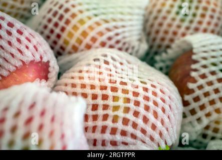 Mele avvolte con polistirolo, materiale di imballaggio non ecologico. Foto Stock