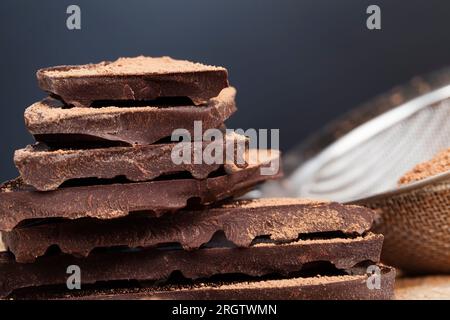 cioccolato amaro spezzato a pezzi, grandi pezzi di cioccolato amaro con cacao e burro, diviso in pezzi un pezzo di cioccolato di cacao Foto Stock