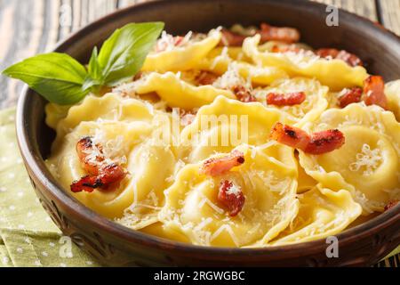 Pasta Girasoli a forma di girasoli con formaggio, basilico e pancetta sul piatto sul tavolo di legno. Orizzontale Foto Stock