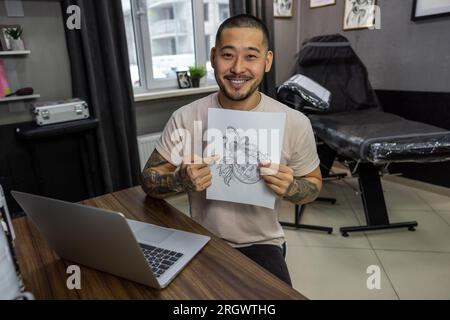 Giovane con tatuaggi che lavora su un notebook Foto Stock