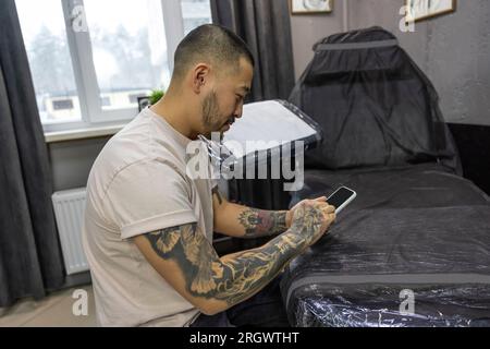 Giovane con tatuaggi che lavora su un notebook Foto Stock