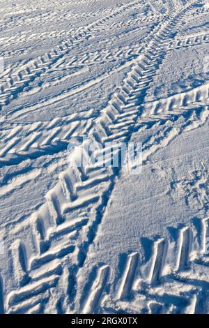una strada ricoperta di neve in inverno, tracce lasciate nella neve dalle auto su una strada non sbucciata dopo una nevicata Foto Stock