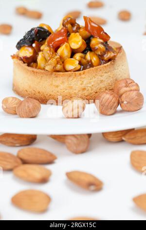 crostata di grano con ripieno dolce, croccante croccante con nocciole, arachidi e altri ingredienti, crostata di pasta di grano con noci e frutta secca in crea Foto Stock