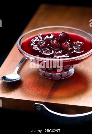 marmellata di ciliegie fatta in casa in una piccola ciotola con piedistallo in vetro Foto Stock