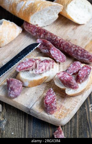 i pezzi di salsiccia affettati di carne sono sdraiati su un tagliere, la carne di maiale con la pancetta è secca e appassita, la carne è pronta per mangiare Foto Stock