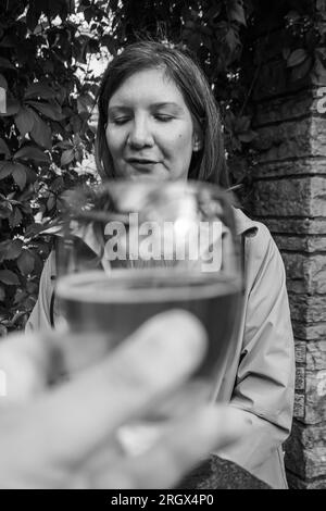 Mano corta che regge il drink davanti a una persona Foto Stock