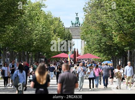 Berlino, Germania. 11 agosto 2023. Passanti a piedi nella riserva centrale della strada Unter den Linden sullo sfondo della porta di Brandeburgo. Credito: Soeren Stache/dpa/Alamy Live News Foto Stock