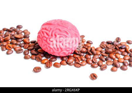 Mucchio di chicchi di caffè tostati e una replica di cervello umano rosa isolato su sfondo bianco. Concetto di dipendenza creativa dal caffè. Foto Stock