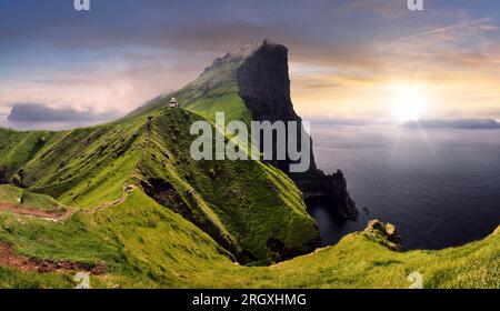 Tramonto sulla verde montagna con l'oceano atlantico, le isole Faroe - faro di Kallur Foto Stock