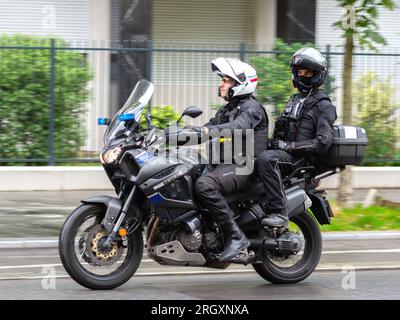 Motocicletta della polizia senza contrassegno con due agenti in via centrale - Paris 16, Francia. Foto Stock