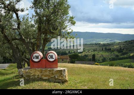 Piccole botti rosse con scritto vino e olio sotto un olivo nella regione del Chianti Classico vicino a Panzano in Chianti, Italia. Foto Stock