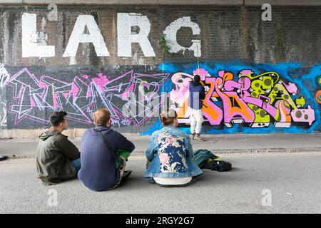 Birmingham, Regno Unito. 12 agosto 2023. Artisti di graffiti al lavoro su pareti abbandonate nel quartiere Digbeth di Birmingham, Regno Unito, come parte dell'High Vis Street Art Festival. Decine di graffiti spray di strada possono artisti scendere in città ogni anno per lasciare il loro segno. Crediti: Peter Lopeman/Alamy Live News Foto Stock