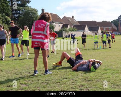 Kesgrave, Suffolk - 12 agosto 2023: 400th Park Run di Kesgrave al Millennium Field. Corridore esausto sdraiato sull'erba alla fine. Foto Stock