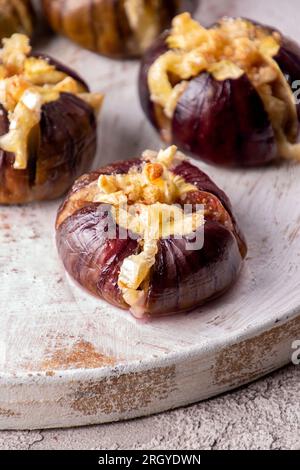 Fichi maturi cotti al forno con formaggio mucca brie e camambert e cosparsi di pangrattato decorato con foglie di menta su sfondo bianco. Eati sani Foto Stock