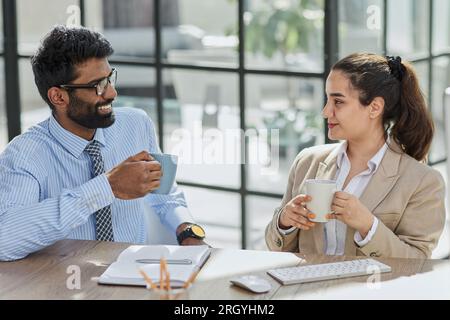 i colleghi parlano durante la pausa pranzo mentre sono seduti sul posto di lavoro Foto Stock