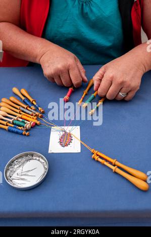 Mani di persone che preparano e preparano il merletto a bobina. Fili di pizzo colorati. Attività ricreative. Foto Stock