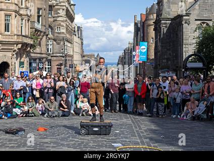 Royal Mile, Edimburgo, Scozia, Regno Unito. 12 agosto 2023. Edinburgh Festival Fringe, artisti di strada di High Street che si esibiscono per un grande pubblico, ventoso per chi si trova su piattaforme, sole e docce pesanti occasionali. Nella foto, Reidiculous si schiaccia le fruste per il pubblico di High Street. Credito: Notizie dal vivo Archwhite/alamy. Foto Stock