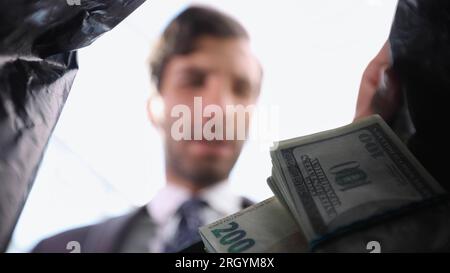 un uomo d'affari prende i soldi da un sacchetto di plastica. Foto Stock