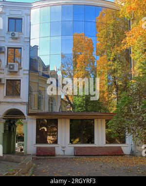 La foto è stata scattata nel parco di Odessa chiamato Palais Royal in autunno. L'immagine mostra la facciata in vetro dell'edificio, che riflette gli alberi Foto Stock