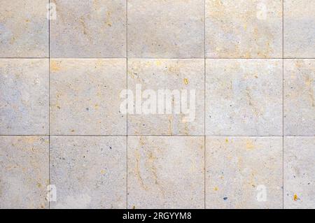 Una parete piastrellata con piastrelle quadrate, beige e sottili linee bianche di Malta. Foto Stock