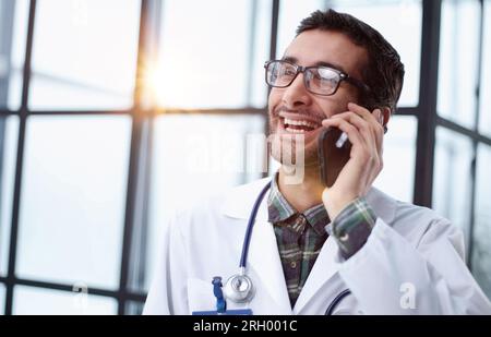 Telefonata, medico di sesso maschile che fa una visita di telesorma nel suo ufficio in ospedale. Foto Stock