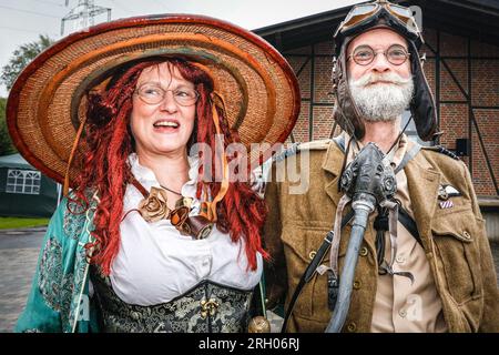 Henrichenburg, Waltrop, Germania. 12 agosto 2023. Due partecipanti sono venuti ben preparati per la pioggia. Gli appassionati di steampunk, i gruppi in costumi e i visitatori, molti in abiti retrò-futuristici o di ispirazione vittoriana, si divertono nonostante le forti docce a pioggia del primo giorno del weekend del Festival del Giubileo di Steampunk presso lo storico skilift di Henrichenburg, un monumento architettonico e sito del patrimonio industriale. Crediti: Imageplotter/Alamy Live News Foto Stock